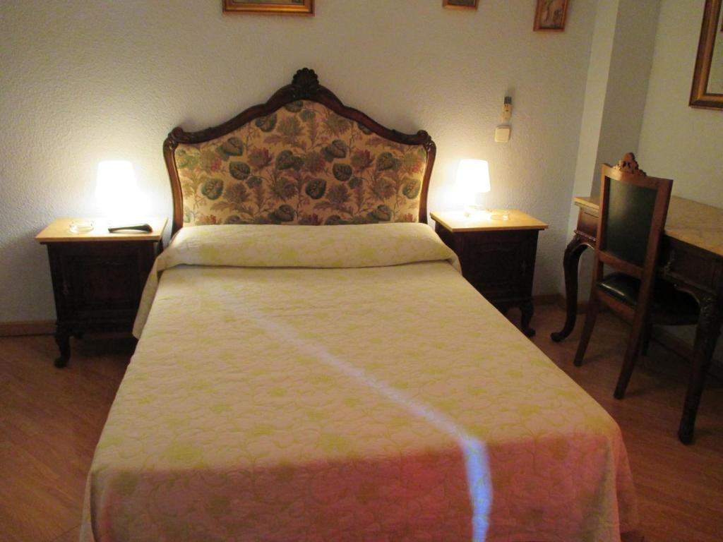 1 dormitorio con 1 cama con 2 mesas y 2 lámparas en Hostal Pradillo, en Móstoles