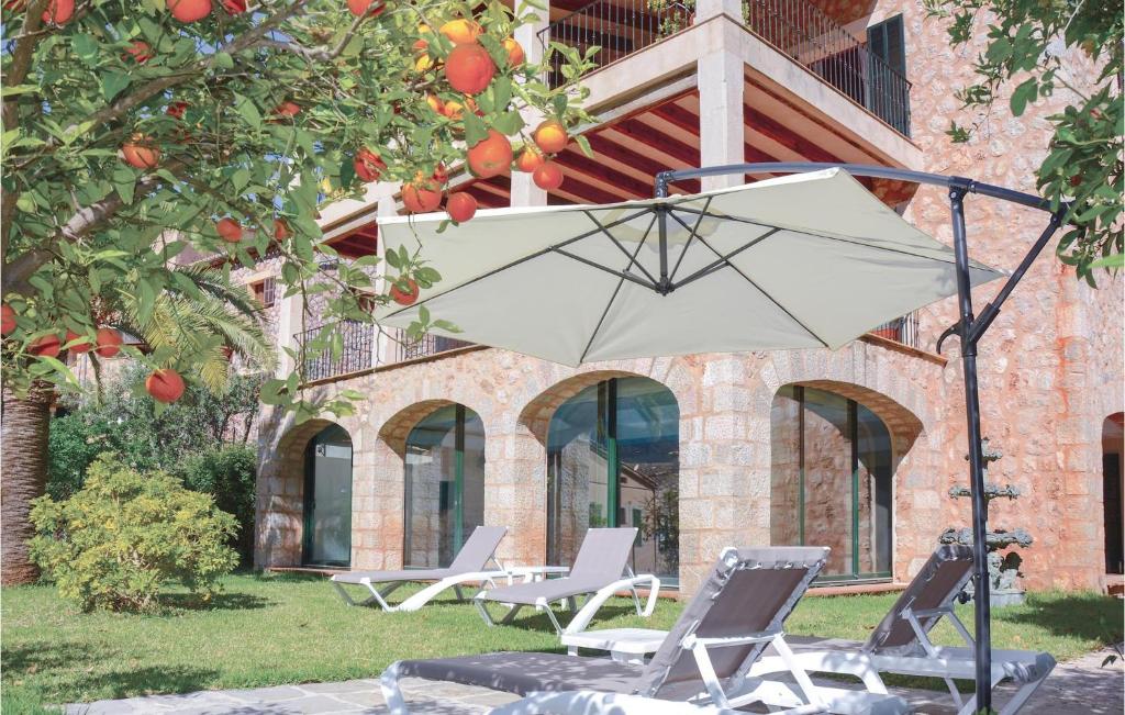 grupa krzeseł i parasol przed budynkiem w obiekcie 4 Bedroom Stunning Home In Fornalutx w mieście Fornalutx