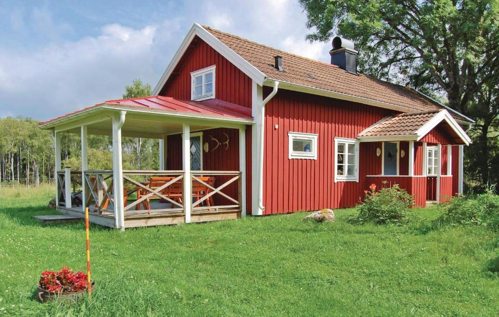 een rood huis met een veranda op een tuin bij Amazing Home In Blidsberg With Kitchen in Blidsberg