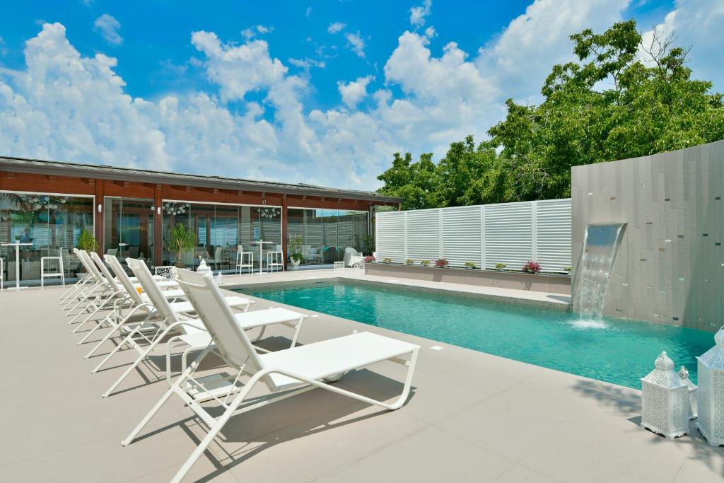 a pool with white lounge chairs next to a building at Best Western Hotel Ferrari in Nola