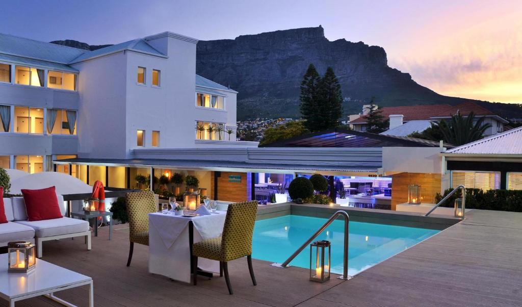 a hotel patio with a table and chairs and a pool at The Cape Milner in Cape Town