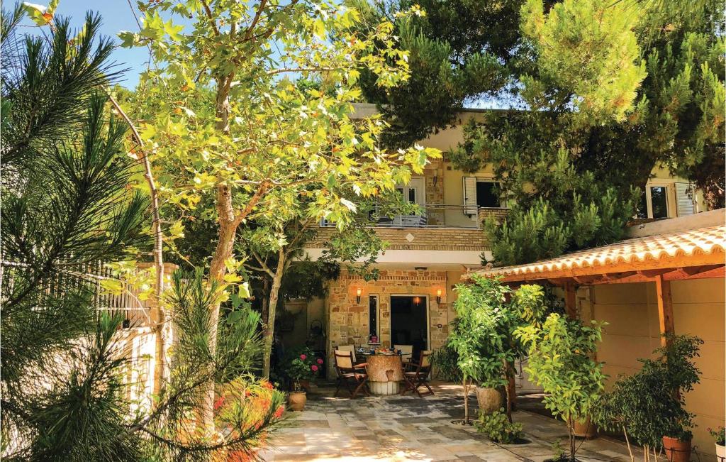 ein Haus mit einer Terrasse und Bäumen davor in der Unterkunft Amazing Home In Artemida With Kitchen in Artemida