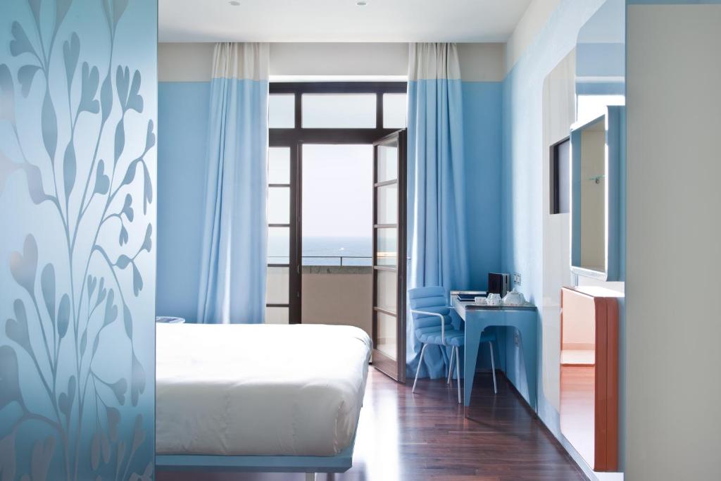 Schlafzimmer mit einem Bett, einem Schreibtisch und einem Fenster in der Unterkunft JR Hotels Bari Grande Albergo delle Nazioni in Bari
