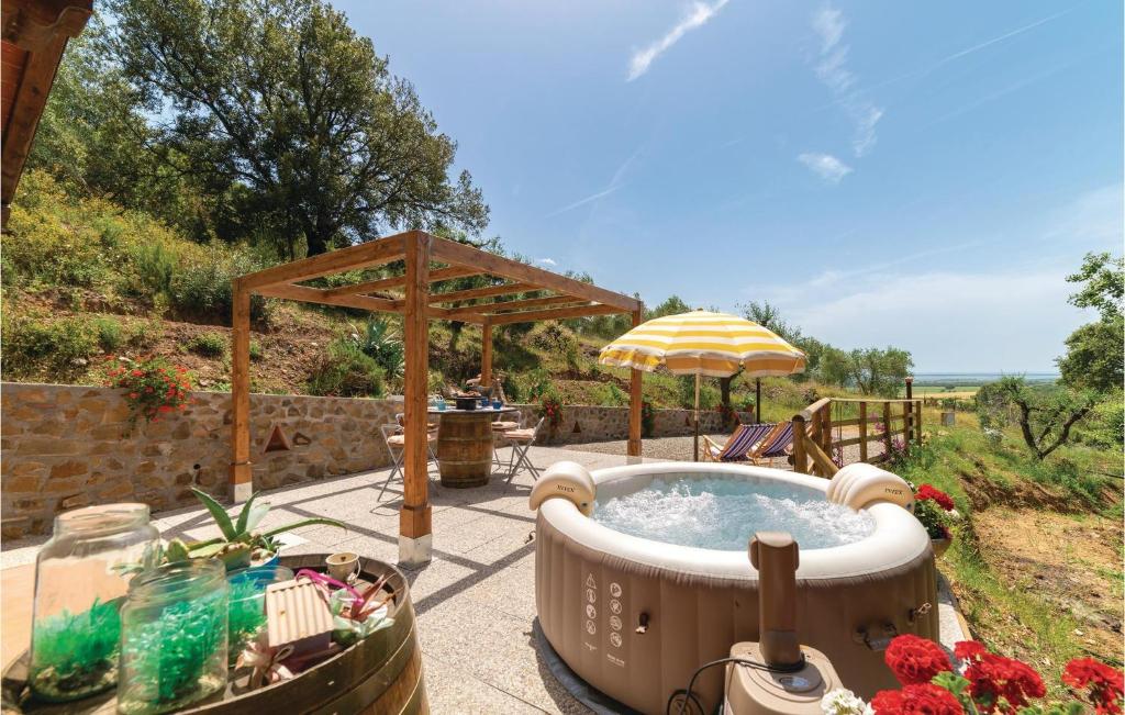 a hot tub in a garden with an umbrella at Laguna Celeste in Vetulonia