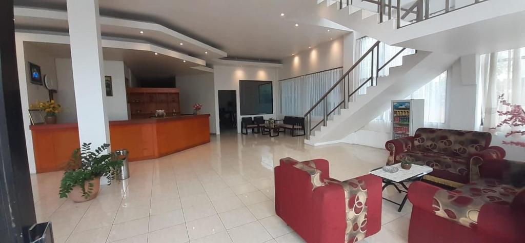 a living room with red chairs and a staircase at Tiara Inn in Ternate