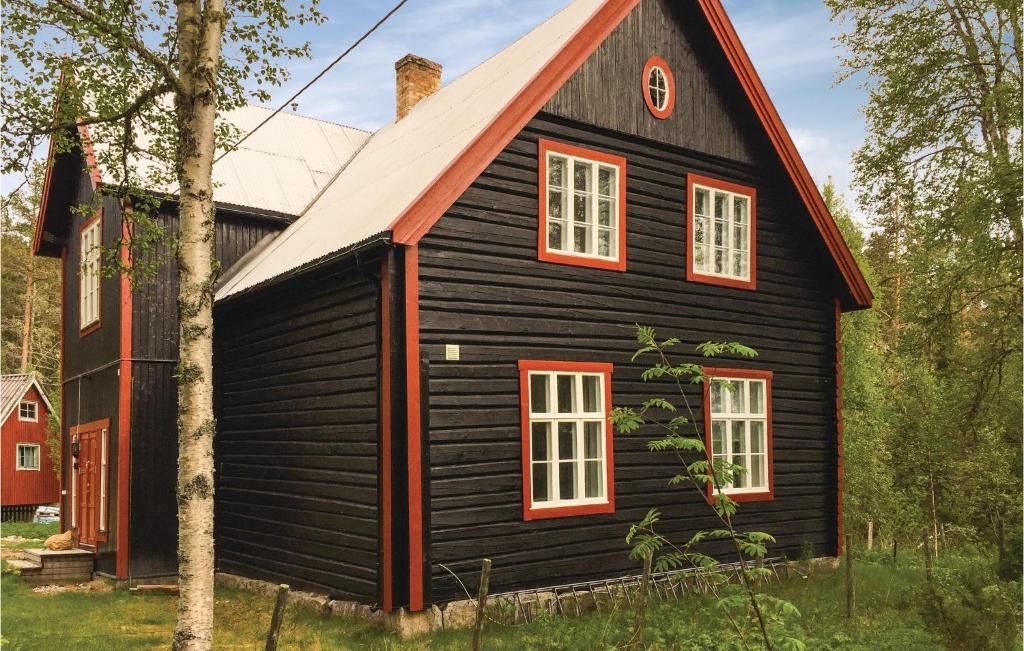 uma casa preta com um telhado vermelho em Cozy Home In Engerdal With House A Mountain View em Femundsundet