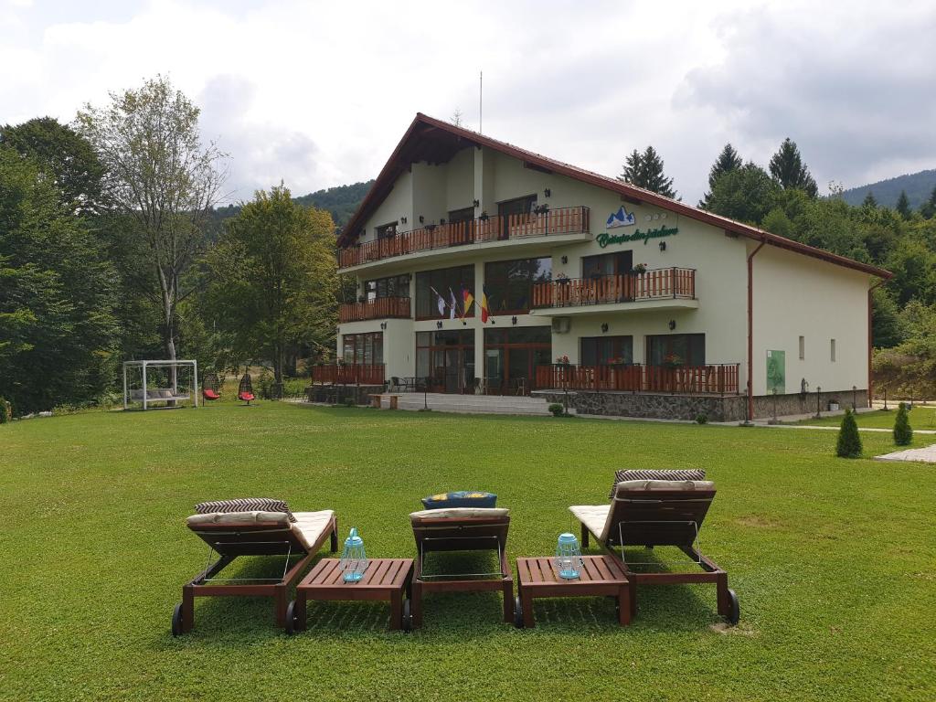 a building with three picnic tables in front of it at Casuta Din Padure in Drăguş
