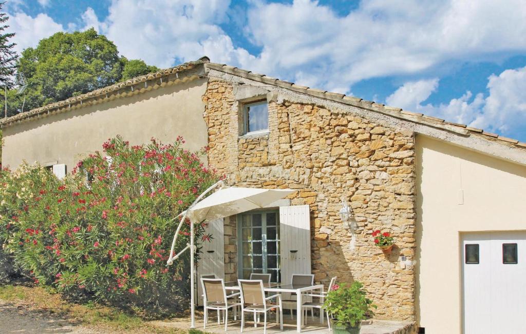 a stone house with chairs and an umbrella at 2 Bedroom Stunning Home In St-andr-dolrargues in La Roque-sur-Cèze