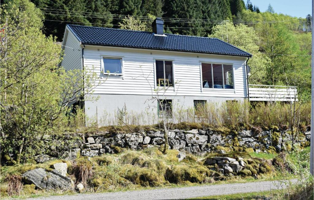 a white house on a hill with a stone wall at Gorgeous Home In Eivindvik With Kitchen in Eivindvik