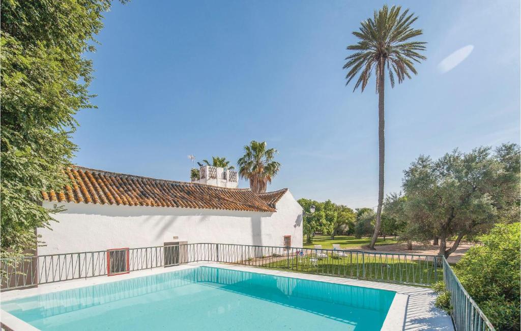 a swimming pool next to a building with a palm tree at Amazing Home In La Campana, Sevilla With 5 Bedrooms, Outdoor Swimming Pool And Swimming Pool in La Campana