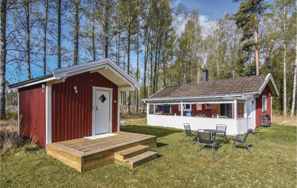 un pequeño cobertizo rojo y blanco con mesa y sillas en Cozy Home In Hammar With Kitchen, en Hammarö