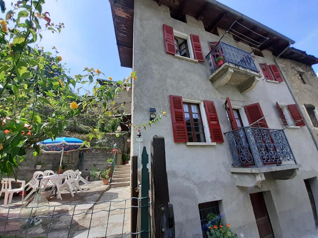 a building with red windows and a table and an umbrella at Occitania in Gravere