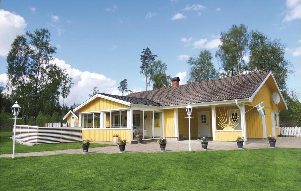 una casa gialla con un prato di fronte di Cozy Home In Oskarstrm With Kitchen a Karlstorp