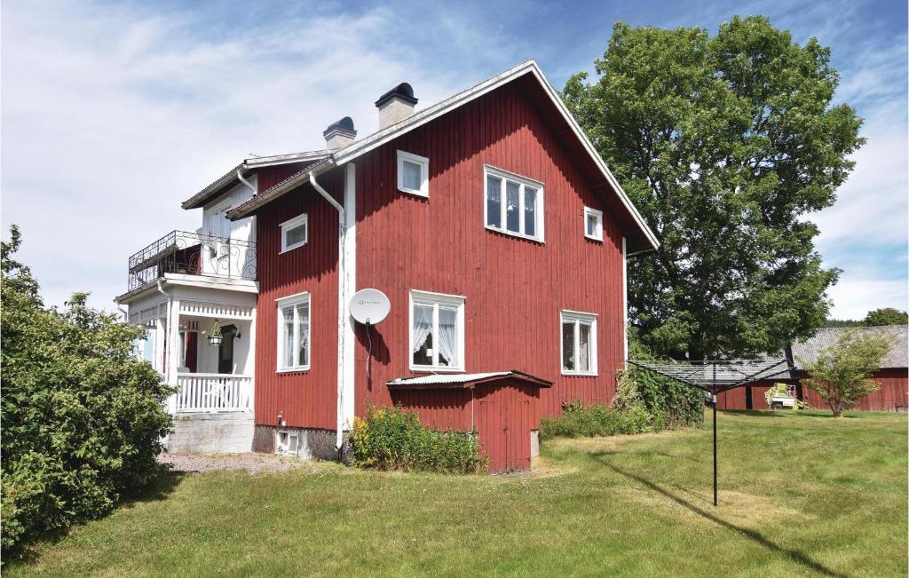 ein rotes Haus mit weißen Fenstern auf einem Feld in der Unterkunft Nice Home In ml With House A Mountain View in Åmål