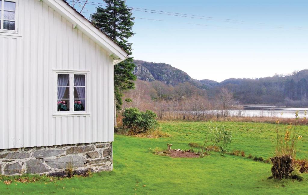 une maison blanche avec une fenêtre et un champ vert dans l'établissement Awesome Home In Farsund With Lake View, à Helle