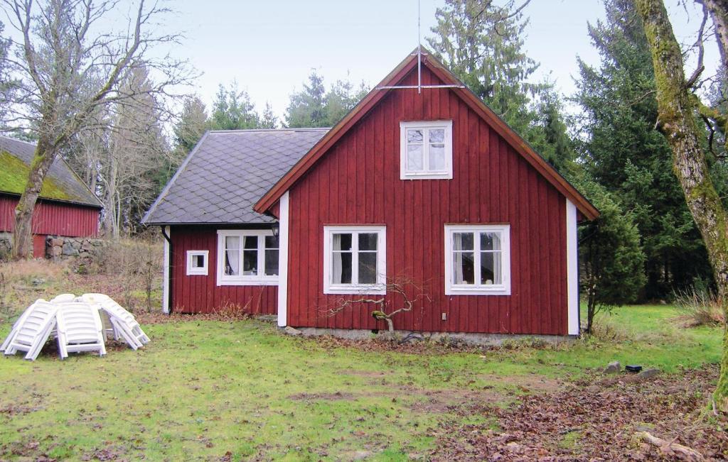 a red barn with two white windows and a table at Nice Home In Lidhult With Kitchen in Ljunghult