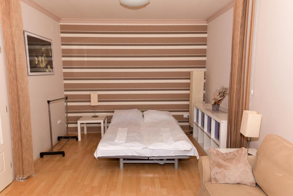 ハイドゥソボスローにあるArt Erika Apartmentのベッド1台とソファが備わる小さな客室です。
