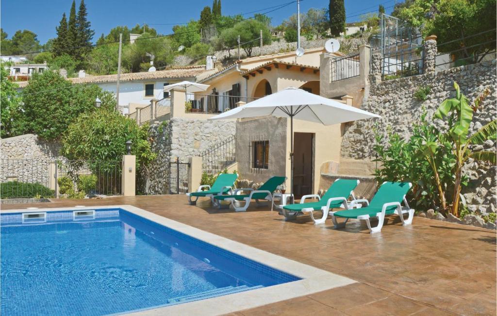 a swimming pool with chairs and an umbrella next to a house at Beautiful Home In Galilea With Outdoor Swimming Pool in Galilea