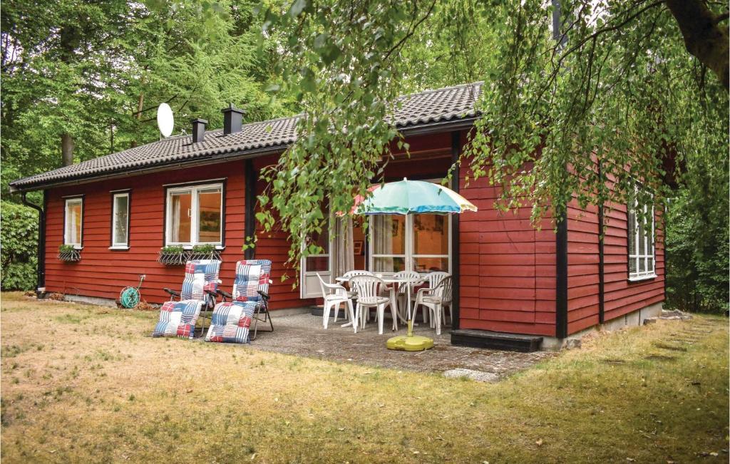 HjärnarpにあるLovely Home In Hjrnarp With Wifiの赤いキャビン(テーブル、椅子、パラソル付)