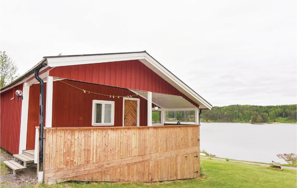a red house with a wooden fence in front of a lake at Beautiful Home In Klssbol With 2 Bedrooms And Wifi in Prästhög