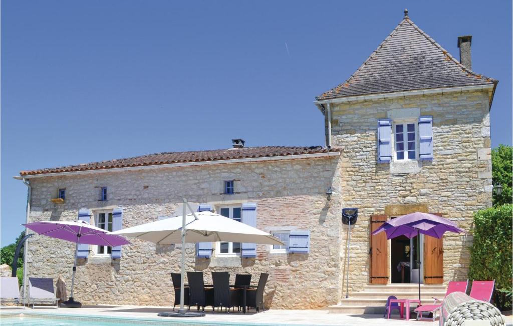 a building with chairs and umbrellas next to a pool at Awesome Home In Puy Levque With Private Swimming Pool, Can Be Inside Or Outside in Puy-lʼÉvêque