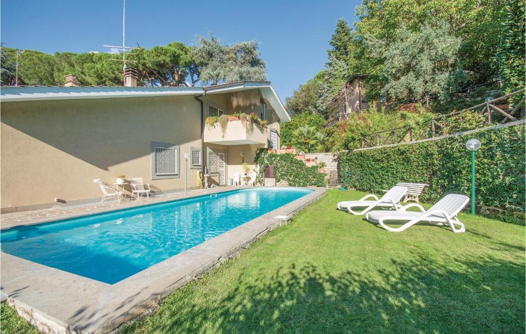 a swimming pool with two lawn chairs and a house at Carlotta in Grottaferrata