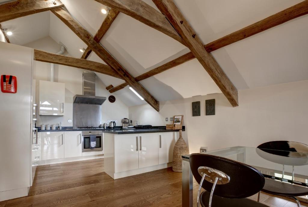 a kitchen with white cabinets and wooden beams at The Threshing Barn in Pwllheli