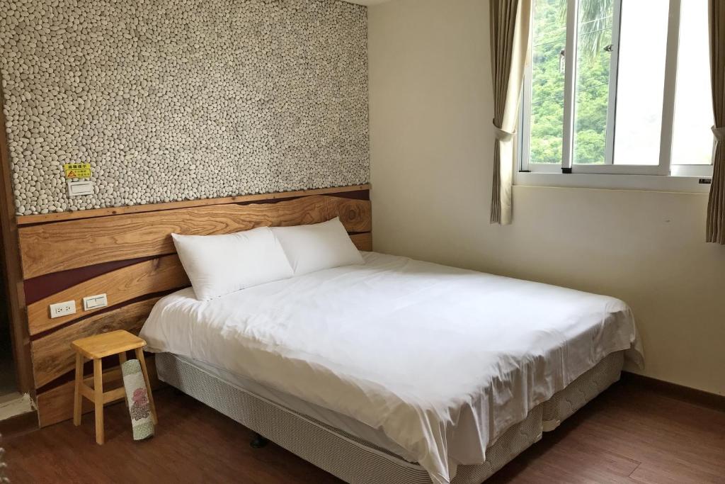 ein kleines Schlafzimmer mit einem Bett und einem Fenster in der Unterkunft Chihpen Lucky Hot Spring B&B in Wenquan