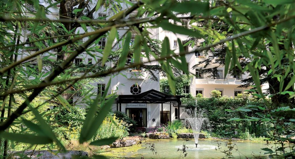 un edificio con un estanque delante de él en Le Grand Hôtel - Domaine De Divonne en Divonne-les-Bains