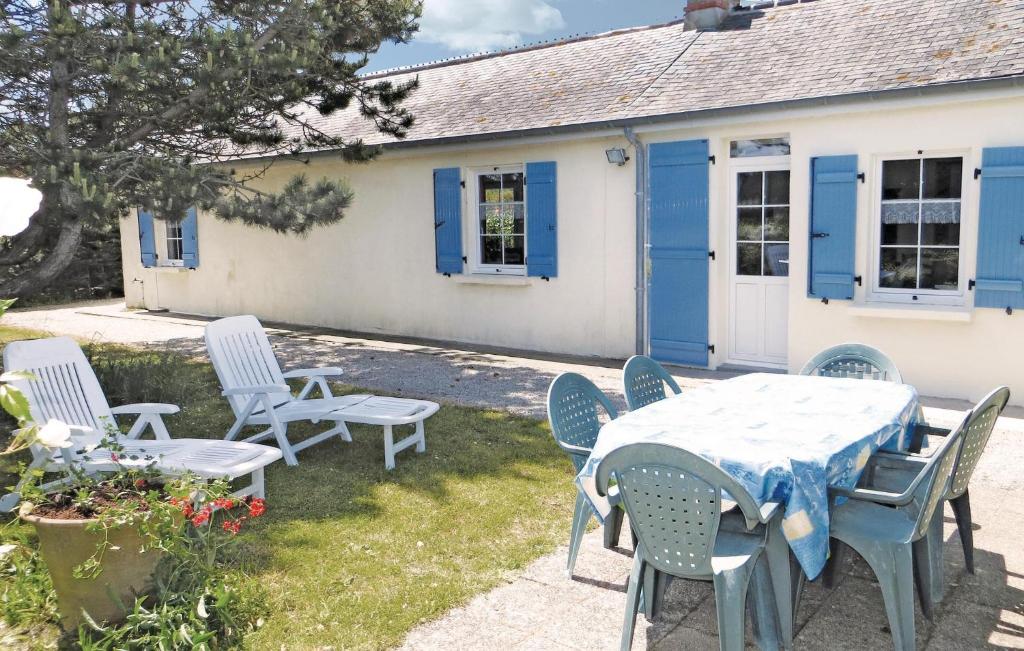 QuinévilleにあるCozy Home In Lestre With Wifiの青いシャッター付きの家の前のテーブルと椅子