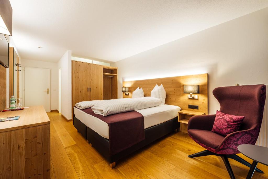 um quarto de hotel com uma cama e uma cadeira em Hotel-Restaurant Bellevue em Flims
