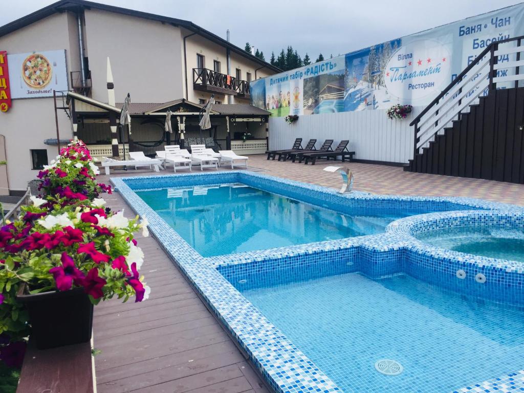 a large swimming pool with flowers in front of a building at Готельний комплекс Парламент, Яблуниця in Yablunytsya