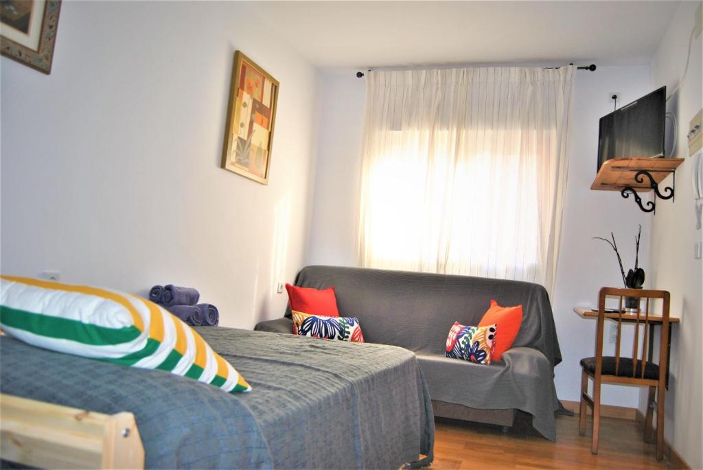 1 dormitorio con cama, sofá y ventana en KHORS, en Málaga