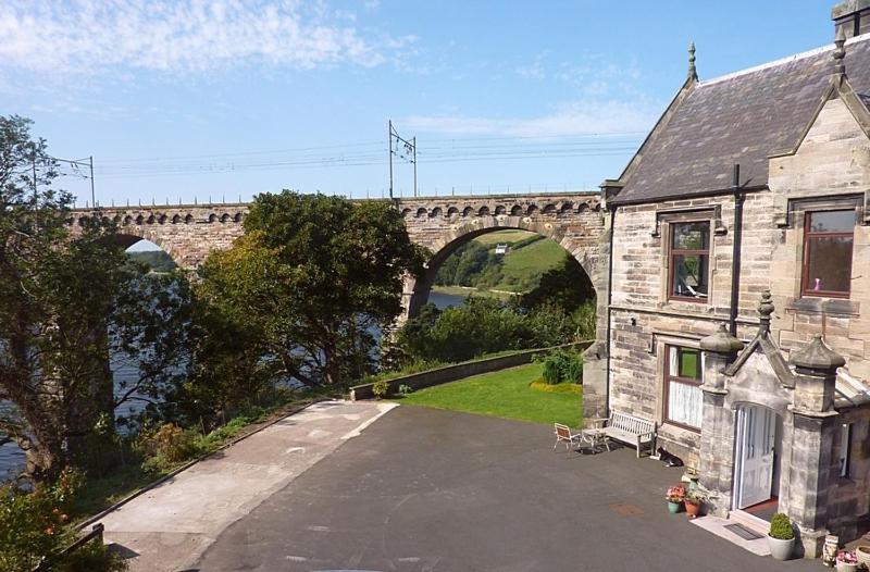 een stenen huis met een brug op de achtergrond bij Castle Vale House in Berwick-Upon-Tweed