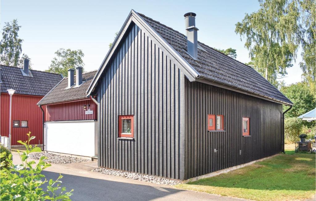 une maison noire avec un garage et une grange rouge dans l'établissement Klitterbyn 16, à Ängelholm