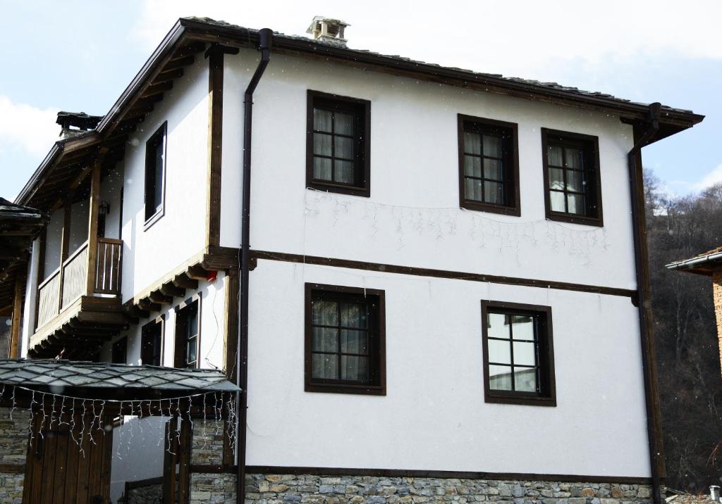 a white house with black windows at Galabova Guest House in Delchevo