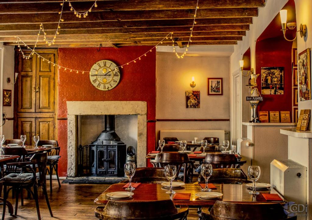 a restaurant with tables and a fireplace and a clock at Forresters Bar & French Restaurant with Rooms in Middleton in Teesdale