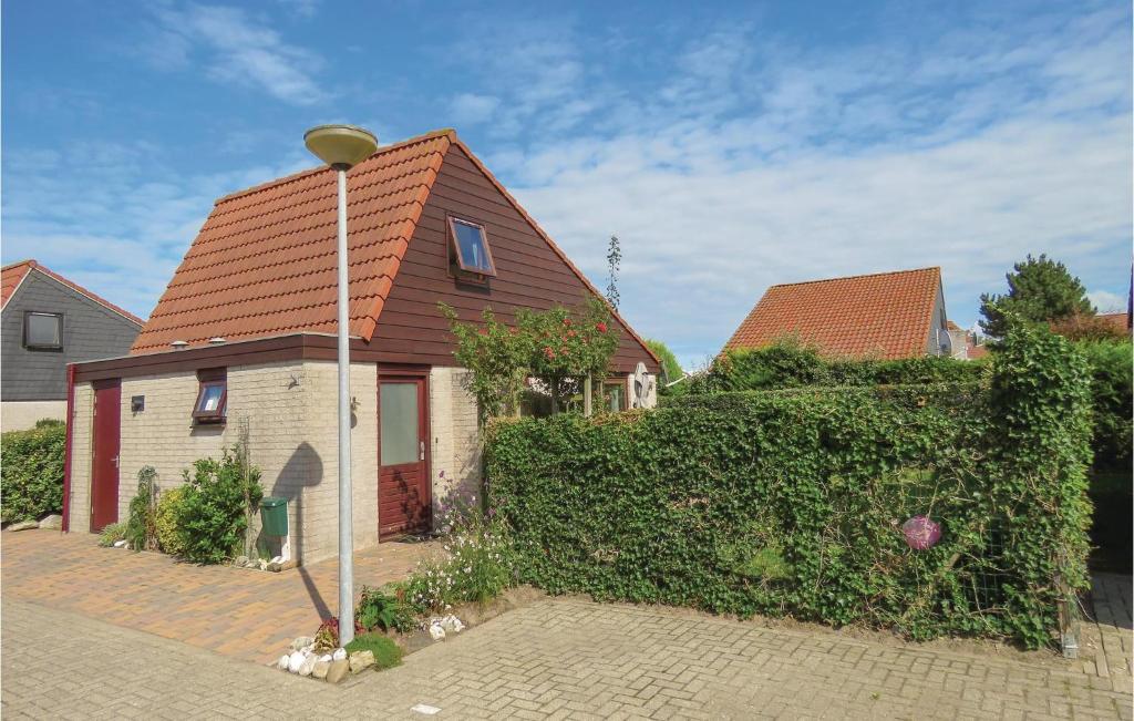 une maison avec un toit rouge et une haie dans l'établissement Pet Friendly Home In Julianadorp With Wifi, à Julianadorp