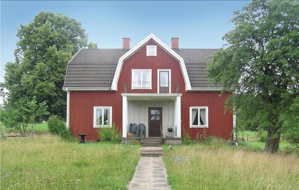 a red house with a white door in a field at 4 Bedroom Awesome Home In Eksj in Berghemmet