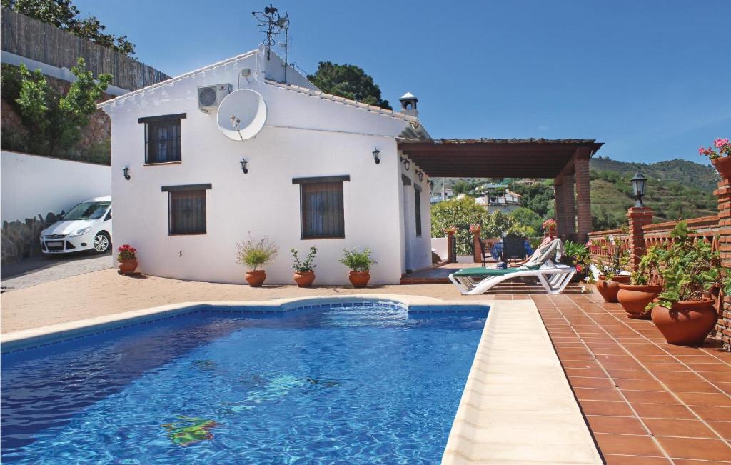 une villa avec une piscine en face d'une maison dans l'établissement Nice Home In Frigiliana With House A Mountain View, à Frigiliana