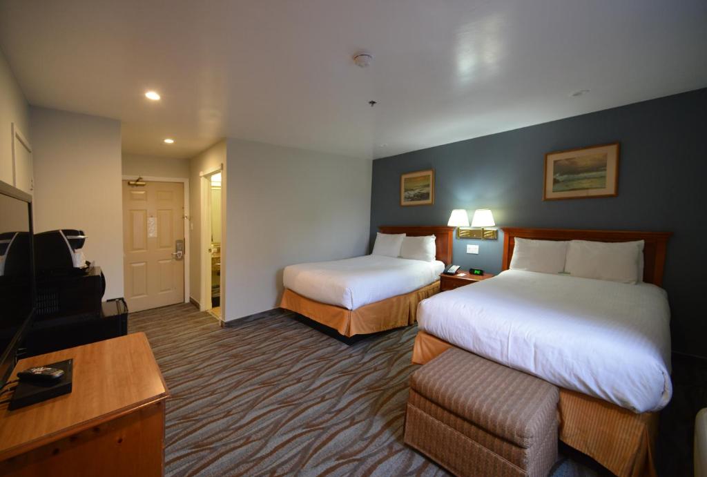 サニーベールにあるチェリー オーチャード インのベッド2台とソファが備わるホテルルームです。