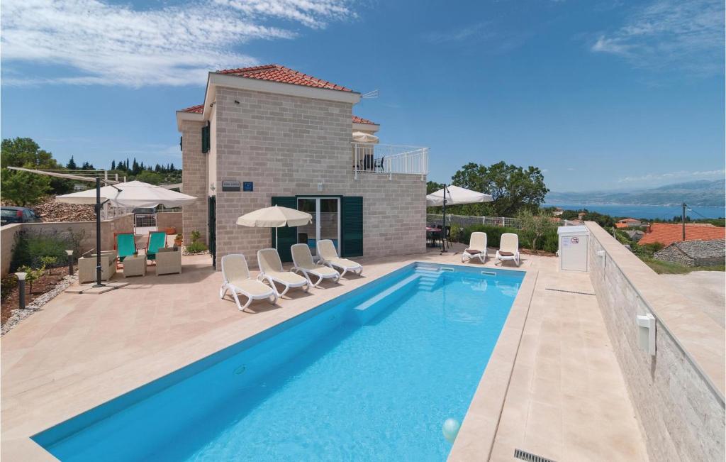 een zwembad met stoelen en een huis bij Cozy Home In Postira With House Sea View in Postira