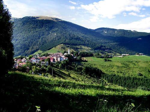 uma pequena cidade numa colina num campo verde em Hotel Monte Fior em Foza