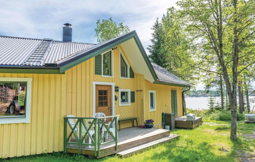 a yellow house with a porch and a deck at 1 Bedroom Gorgeous Home In Lgde in Himmersundet