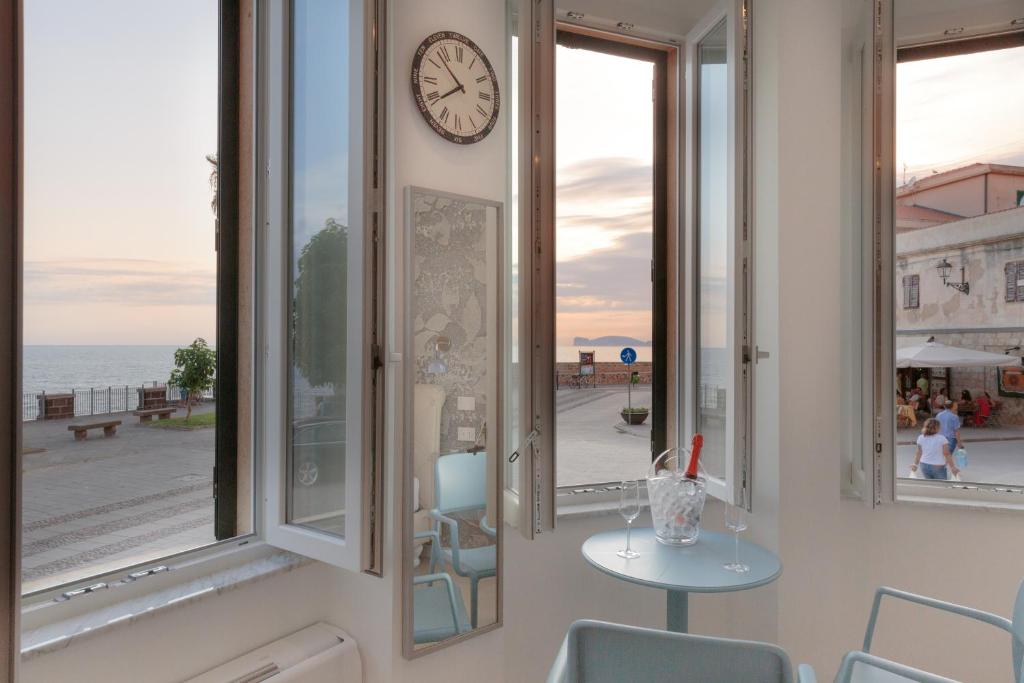 una camera con finestre, tavolo e orologio di Casa Jaume ad Alghero
