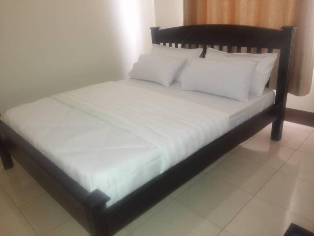 een bed met witte lakens en kussens in een kamer bij Coffee Tourist Motel in Kampala