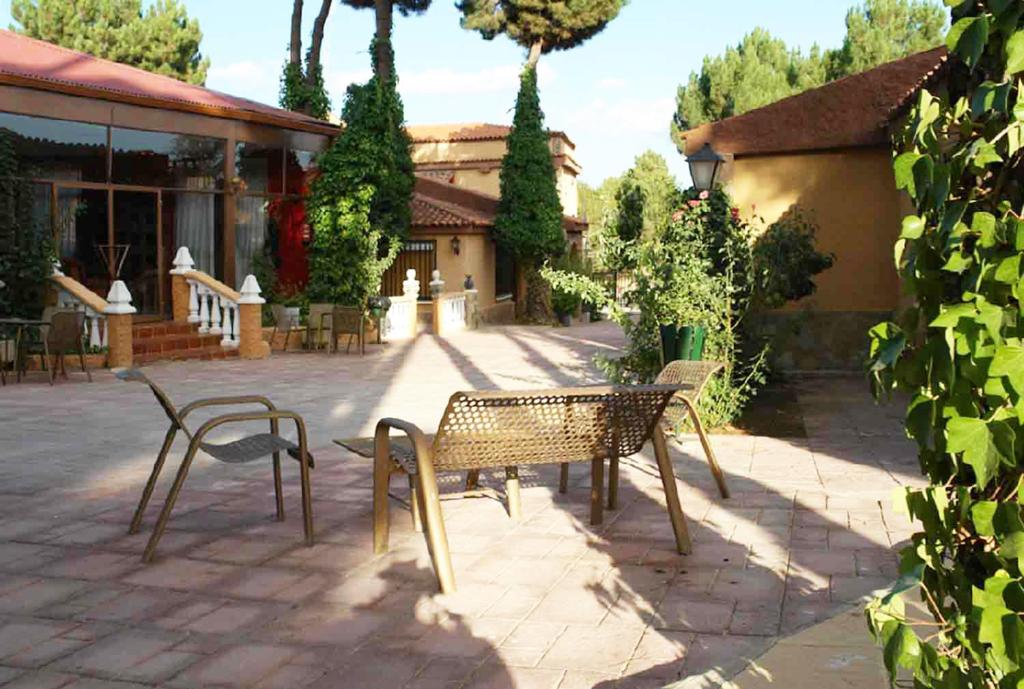 a patio with two chairs and a table and a building at Hotel Rural La villa Don Quijote in Cuenca