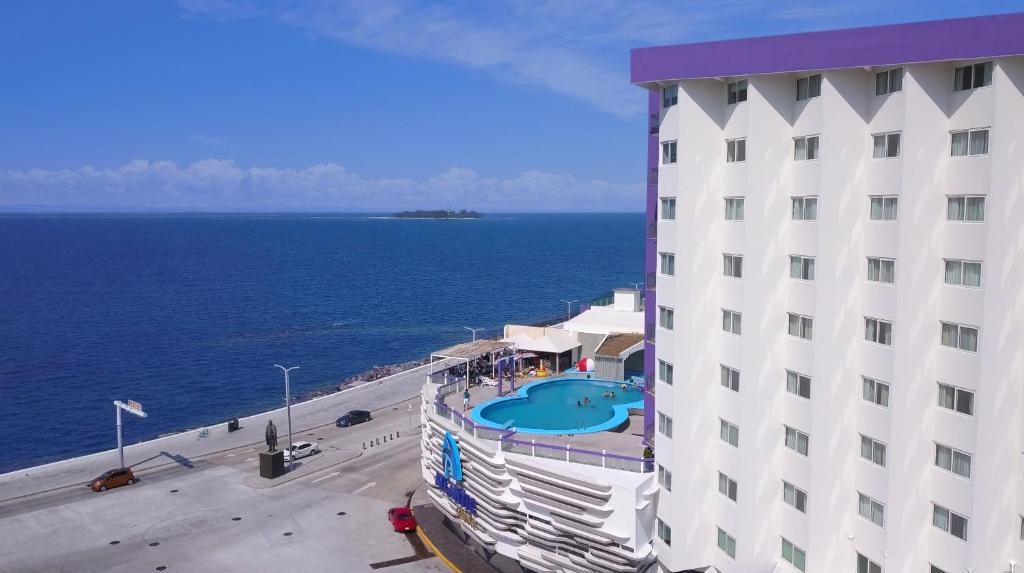 a building with a swimming pool next to the ocean at Hotel Lois Veracruz in Veracruz