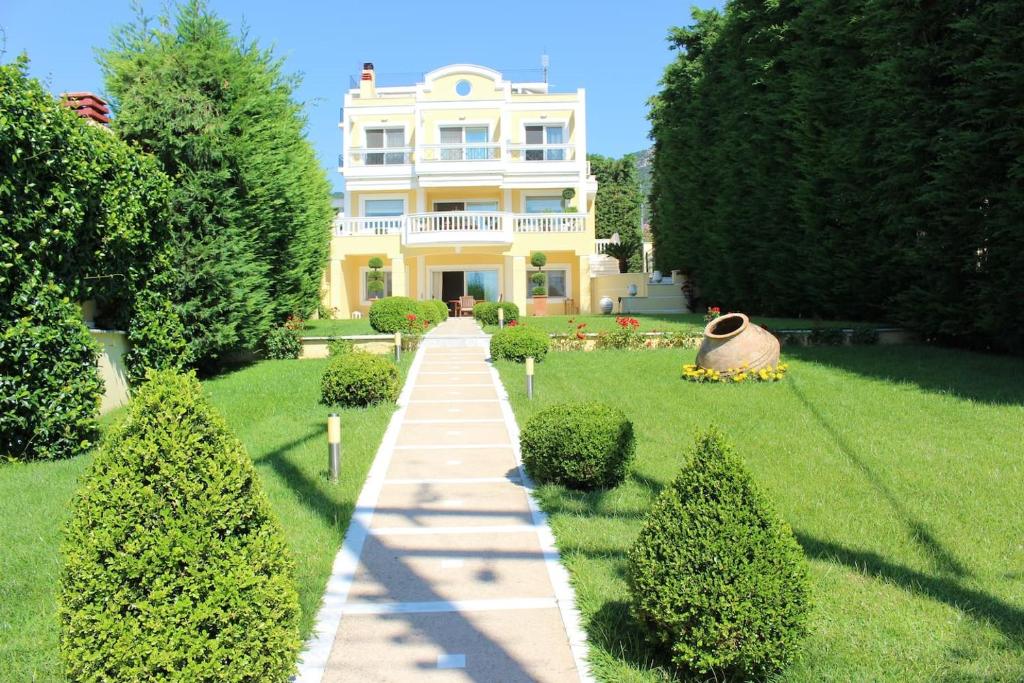 uma grande casa amarela com um caminho no quintal em Shemesh Gardens House em PalaiónTsiflíkion
