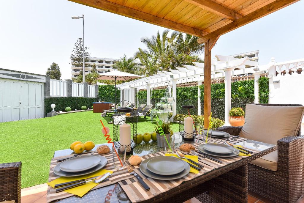 a wooden table with plates of food on a patio at Jacuzzi & Garden Holiday Home in Playa del Ingles